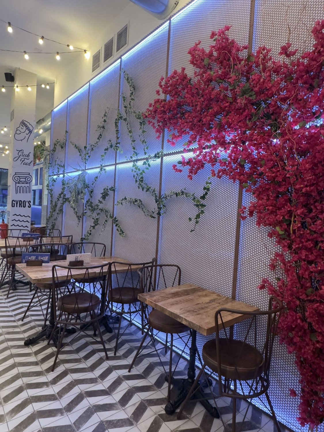 Interior de Gyros con árbol de flor fucsia artificial y enredadera iluminada