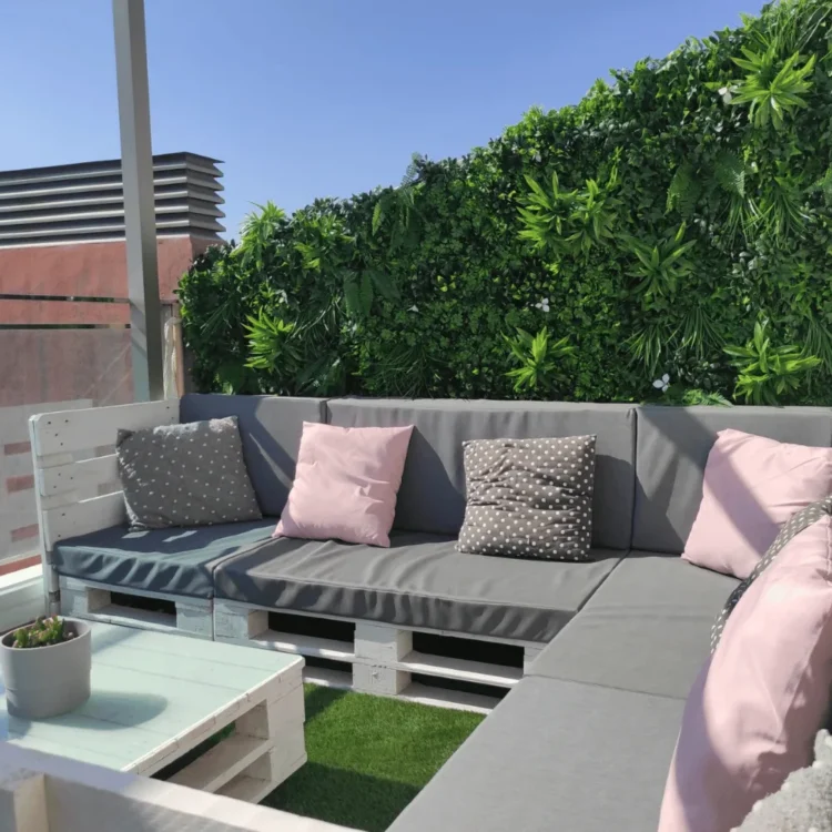 Jardín vertical artificial como cerramiento de una terraza con sofá de palés