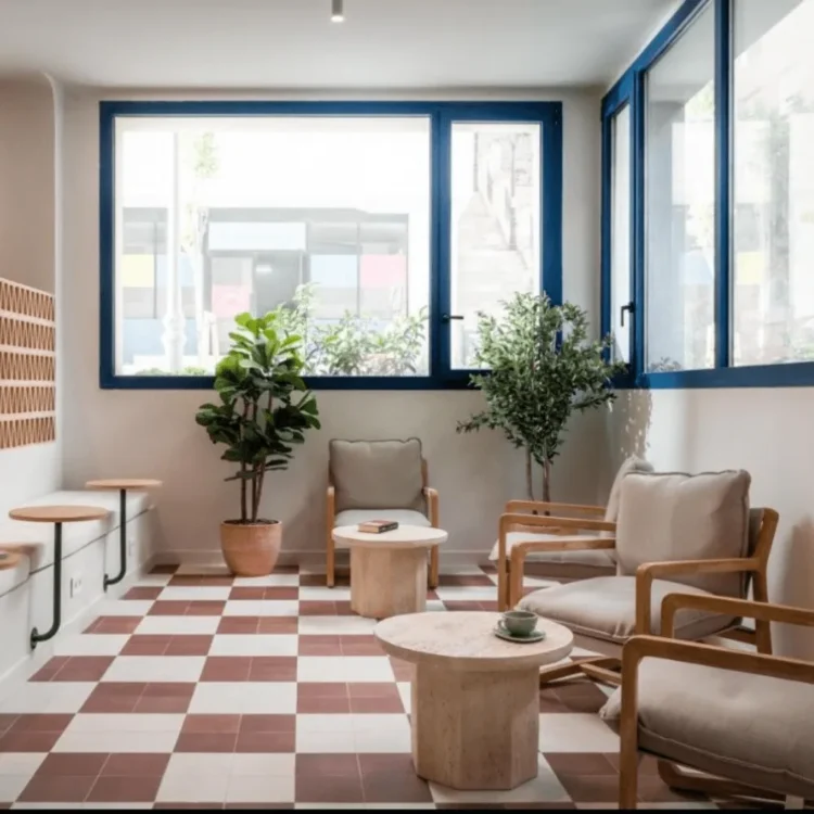 Sala de espera con suelo de damero y árboles artificiales en macetas de barro