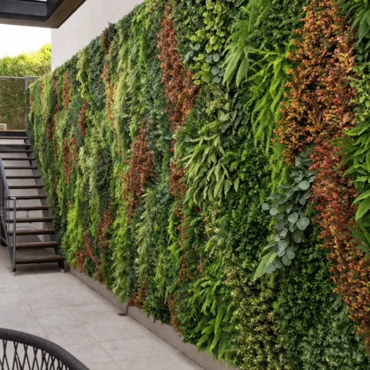 Jardín vertical artificial de gran formato con follaje verde y rojizo en el exterior de una vivienda