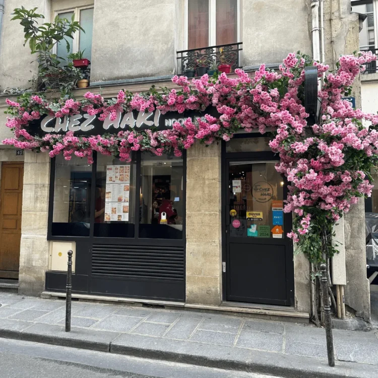 Fachada de un local decorada con flores artificiales rosas sobre la entrada