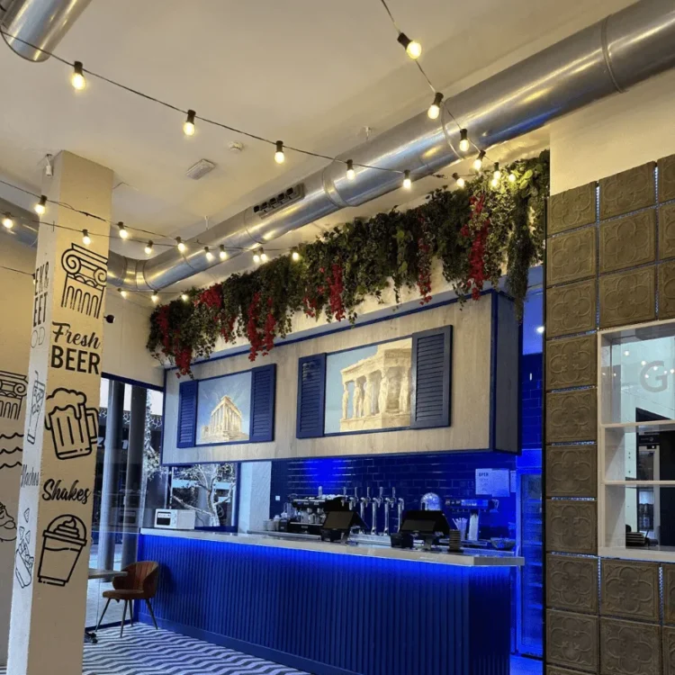 Barra de un bar con guirnalda de vegetación artificial en la parte alta de la pared