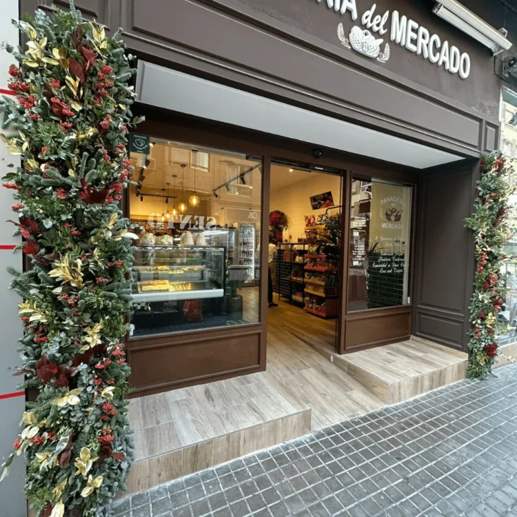 Escaparate de una panadería enmarcado con guirnaldas navideñas artificiales en rojo y dorado