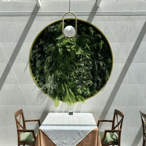 Composición circular de helechos artificiales sobre una mesa de restaurante