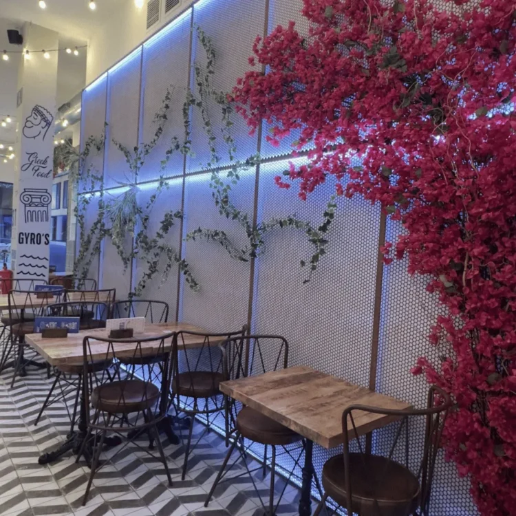 Terraza de un restaurante con buganvilla artificial fucsia sobre la pared