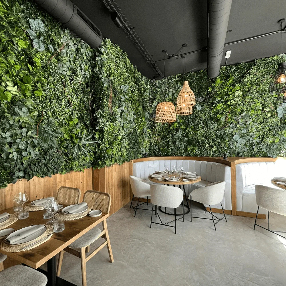 Comedor de restaurante con la pared cubierta de jardín vertical artificial