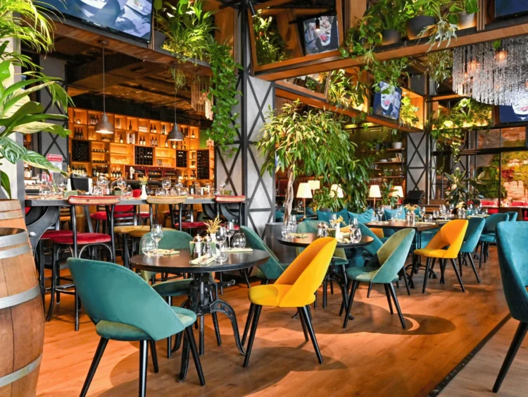 Restaurante con plantas artificiales colgadas de la estructura metálica del techo