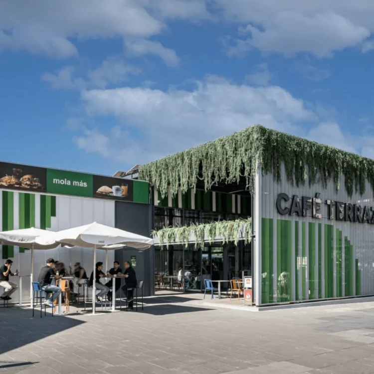 Fachada de un café con cortina de plantas colgantes artificiales sobre la terraza