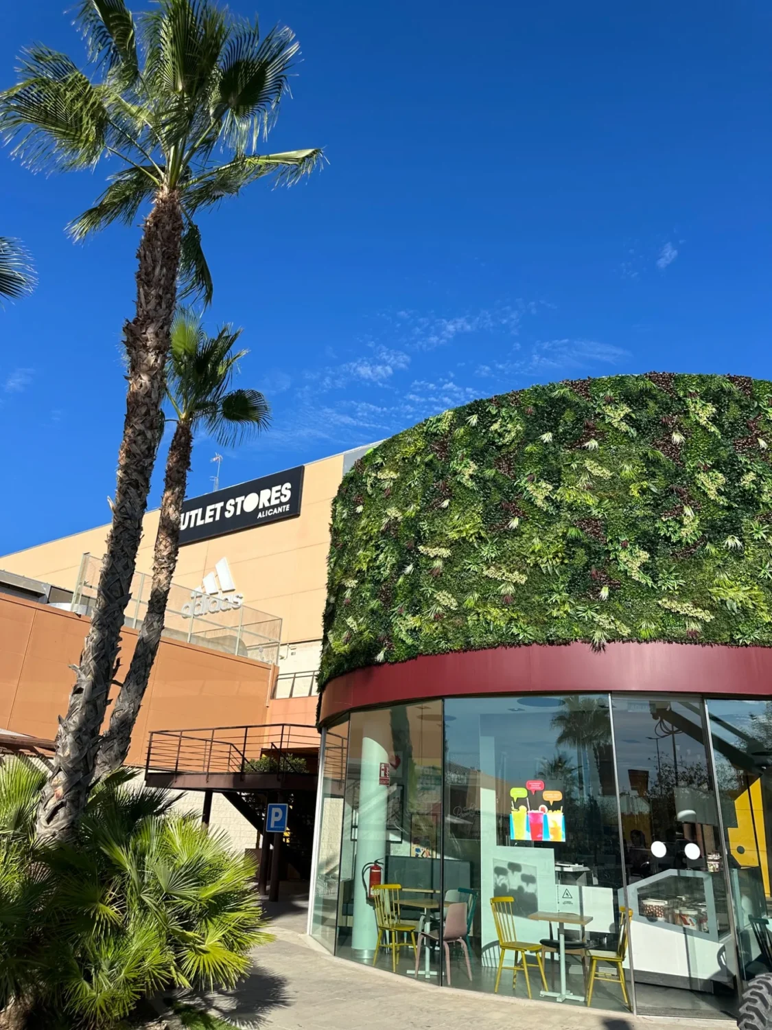 Fachada curva revestida con vegetación artificial en Outlet Stores Alicante