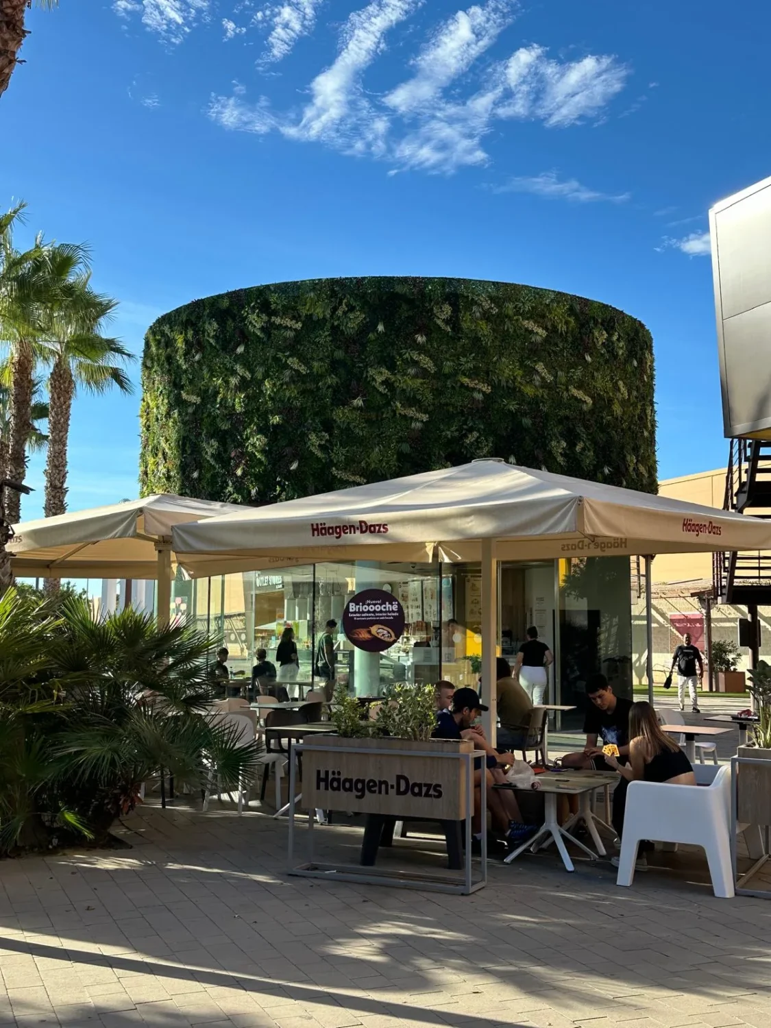 Fachada vegetal artificial exterior junto a terraza en Outlet Stores Alicante